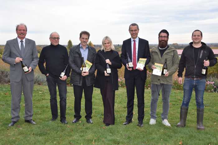 Freuen sich über die weitere Aufwertung der Aktion „Landauer Hochzeitswingert“: Standesamtsleiter Leander Völlinger, Theodor Pfaffmann vom WEIN.GUT.PAN, Peter Büchner von der Galerie Z, Maxime Früh von der Firma Ehrmann, Bürgermeister Dr. Maximilian Ingenthron, Christian Cambeis von der Firma Ehrmann und Thomas Pfaffmann vom WEIN.GUT.PAN (v.l.n.r.). Quelle: Landau in der Pfalz