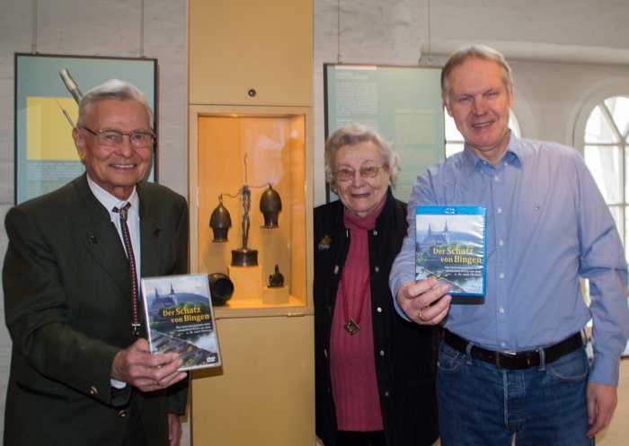 Dr. Karl-Maria Heidecker, Maria Ott-Grimm und Fritz Poppenberg (v. li.) bei der Vorstellung der DVD „Der Schatz von Bingen“. Im Hintergrund ein Teil des Ärztebestecks. Foto: Stadt Bingen