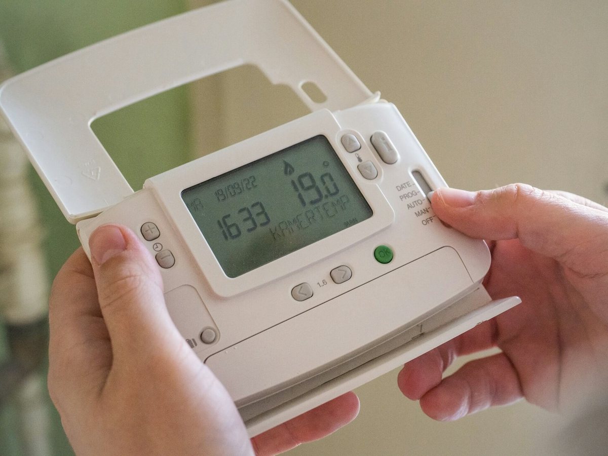 Hände bedienen ein digitales Raumthermostat