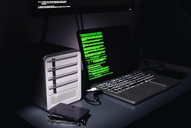 Servergehäuse neben einem Laptop mit Programmcode