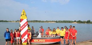 OB Schrempp (li.) und Nicole Würz (vordere Reihe, 3. v. re.) mit der Wachmannschaft des DLRG um das neue Boot am Epplesee. (Foto: Stadt Rheinstetten)