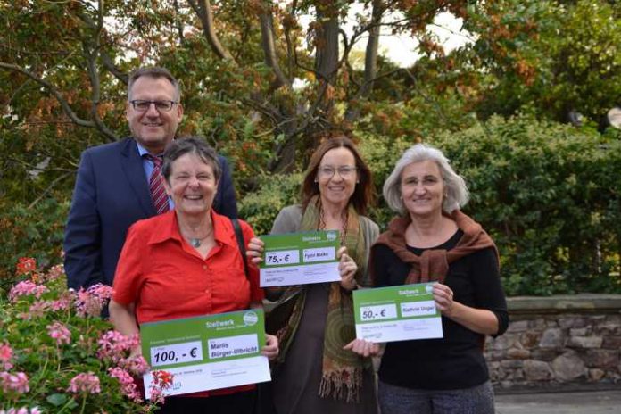 OB Thomas Feser freut sich, Marlis Bürger-Ulbricht den Gewinner-Scheck überreichen zu können. Wiebke Fleischmann (2. v. re.) und Claudia Budinger (re). von der Umweltabteilung der Stadt halten stellvertretend die Schecks der weiteren Preisträger. Foto: Stadt Bingen