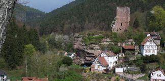 Blick vom Rehfelsen zur Burgruine Elmstein, links unten sieht man die Dächer der Mühle und Wappenschmiede, ein früheres Mühlenensemble mit ehemals fünf Wasserrädern an einem vom Speyerbach abgezweigten Kanal. (Bild: Benno Münch)