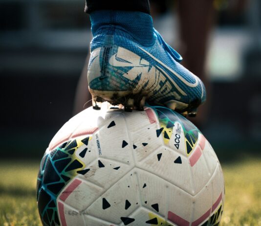 Weißer und blauer Fußball auf grünem Rasenplatz (Unsplash / Connor Coyne)